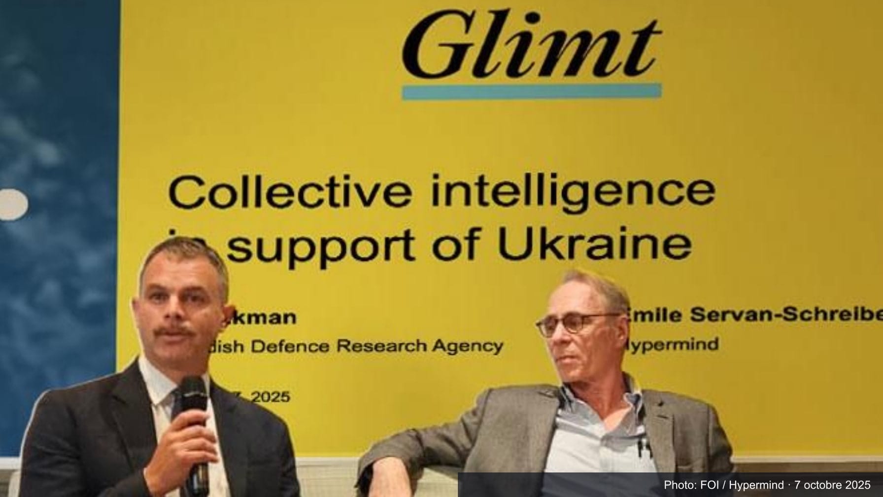 Ivar Ekman holding a microphone beside Émile Servan-Schreiber before a yellow Glimt slide reading “Collective intelligence in support of Ukraine”; dated FOI / Hypermind photo credit.