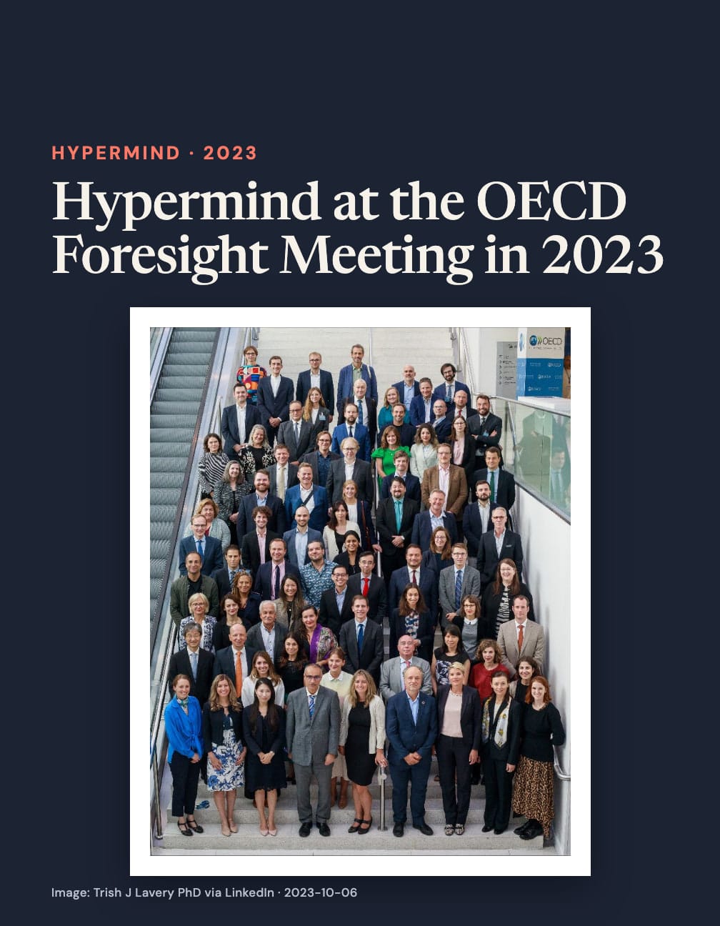“Hypermind at the OECD Foresight Meeting in 2023” appears above a group photograph of dozens of people arranged on an indoor staircase beside an escalator and an OECD sign.