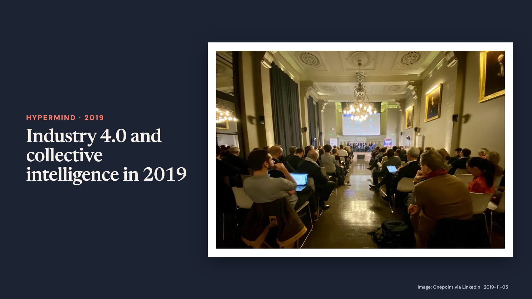 “Industry 4.0 and collective intelligence in 2019” beside a photograph of an audience facing a panel and projection screen in a hall with chandeliers and framed portraits on navy.